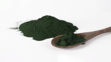 Beyaz arka planda tahta kaşıkta organik spirulina alg tozu..