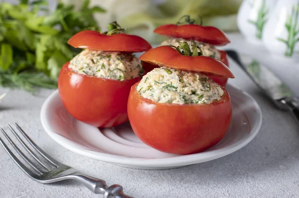 Stuffed tomatoes with cheese, dill and garlic on white plate on a light background. Close-up