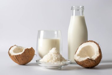 Şişe ve bardakta hindistan cevizi sütü, arka planda taze hindistan cevizi ve gevreği. Vejetaryen yemeği.