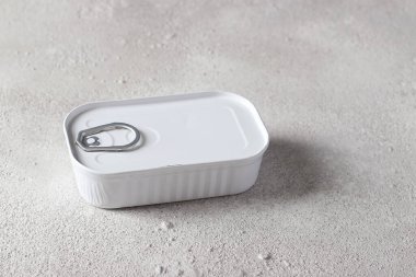 Açık gri arka planda beyaz teneke bir kutuda morina ciğeri. Yatay format. Yakın plan.