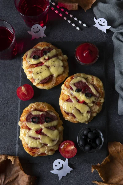 Mini-momies à pizza Halloween avec saucisse et fromage, servies avec olives noires, ketchup et boissons sur carton noir, Vue d'en haut — Photo