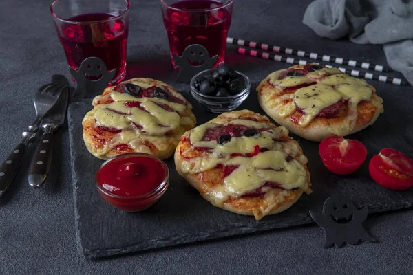 Mumii amuzante de mini pizza cu cârnați și brânză pentru petrecerea de Halloween, servite cu măsline negre, ketchup și băuturi pe fundal gri închis, Close-up — Fotografie, imagine de stoc