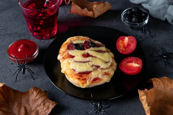 Śmieszna mini pizza mummie z kiełbasą i serem na Halloween party, serwowana z czarnymi oliwkami, ketchupem i napojami na ciemnym tle — Zdjęcie stockowe