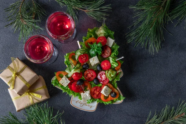 Canapés festivos com pepinos, tomates e queijo servidos em prato como árvore de Natal, em fundo cinza escuro com dois copos de vinho — Fotografia de Stock