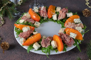 Beyaz tabakta Hamon, hurma, roka ve dor bleu peynirli salata.