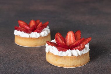 Kahverengi arka planda taze çilekli tartlar.