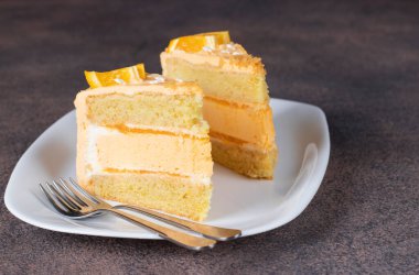 İki parça vanilyalı kek, beyaz tabakta turuncu krema ve krema.