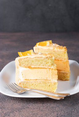 İki parça vanilyalı kek, beyaz tabakta turuncu krema ve krema.