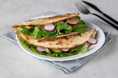 Beyaz tabakta marullu, turplu ve salatalıklı taco.