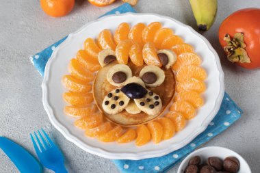 Çocukların kahvaltı sanatı - Aslan gözlemesi mandalinalı, muz ve çikolata beyaz tabakta