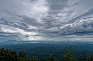A view of mountain under gloomy clouds with rain in distant sky background cloudy in Si Nan National Park, Nan, Thailand clipart