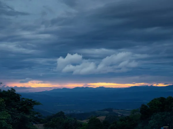 Una vista di una grande montagna sotto le nuvole cupe tramonto nel cielo sfondo carta da parati nuvoloso — Foto Stock