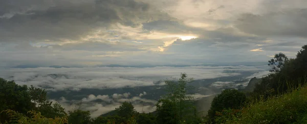 Сумовитий схід сонця купається над долиною гори на схилі пагорба в національному парку Сі Нан (Нан, Таїланд). — стокове фото