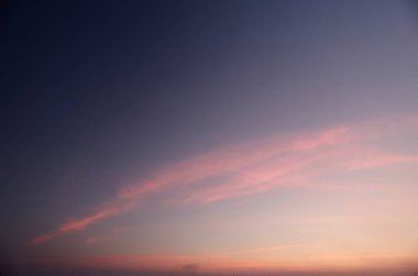 Yalnız bir günbatımı alacakaranlıkta uzun bir buluta karşı.