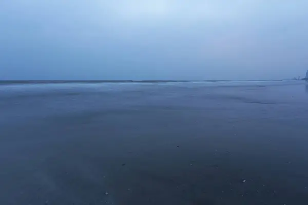 Pusty widok na ocean z odległego miejsca o zmierzchu, samotna wędrówka po ciemnej plaży — Zdjęcie stockowe