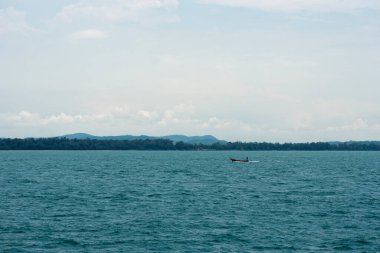 Uzak adanın yakınında okyanusta küçük bir tekne tırabzanı var.