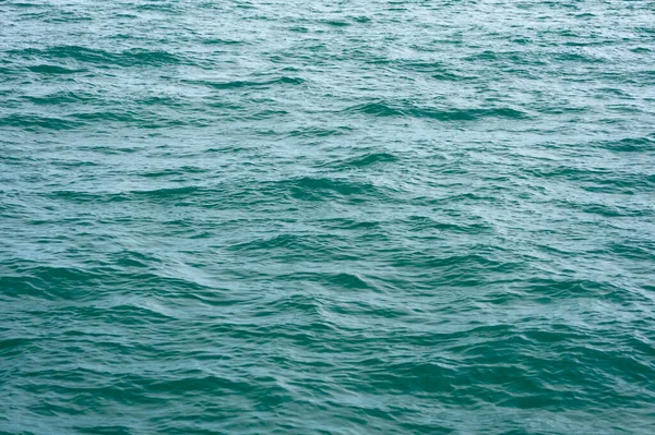 Un primer plano del fondo de pantalla de la superficie de la ola oceánica a la luz del sol —  Fotos de Stock