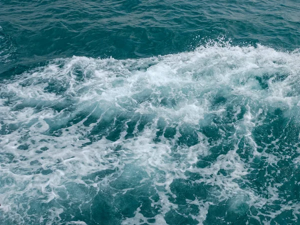 Un primer plano del fondo de pantalla de la superficie de la ola oceánica a la luz del sol — Foto de Stock