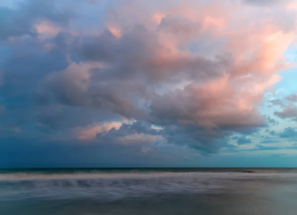 Zachód słońca pomalowany puszystą chmurą nad miękkimi falami długiej ekspozycji — Zdjęcie stockowe