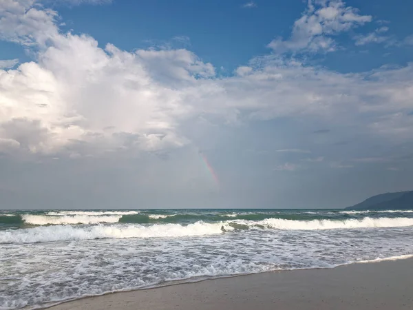 Spokojny ocean plaża zmierzch słońce z tęczą w głębokim błękitnym niebie i bryza fale. — Zdjęcie stockowe