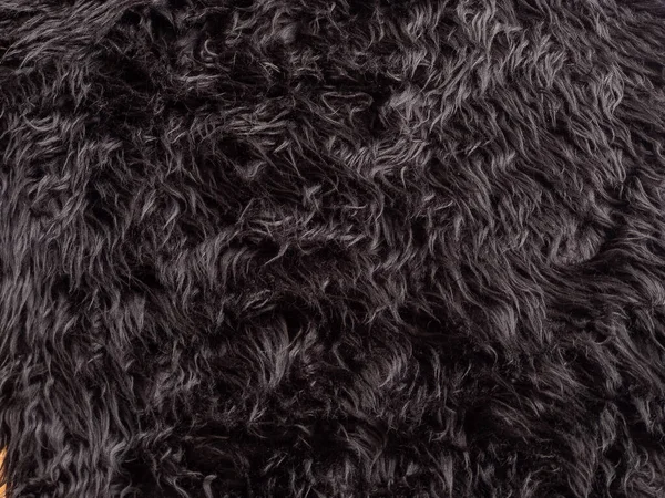 Zwarte dierlijke wol textuur achtergrond. Close-up textuur van pluche pluizig bont tapijt voor product achtergrond, recht zicht — Stockfoto