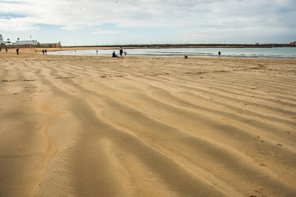 Cadiz, İspanya, 20 Şubat 2020: Atlantik Denizi 'nin soğuk sahillerinde insanların kış yürüyüşleri. İnsanlar sahilde soğuk mevsimde rahatlar.