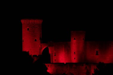 PALMA de MALLORCA, MAJORCA (ISLAS BalEARES), İspanya - 1 Aralık 2020: Bellver Şatosu (Castell de Bellver) Dünya AIDS Günü için kırmızıya boyanmış, Palma şehir merkezinin 3 km batısındaki bir tepede Gotik tarzı bir kaledir.