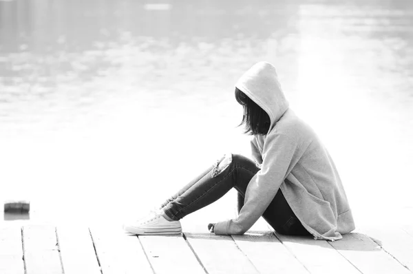 Girl sitting on the dock beside the river — Stock Photo, Image