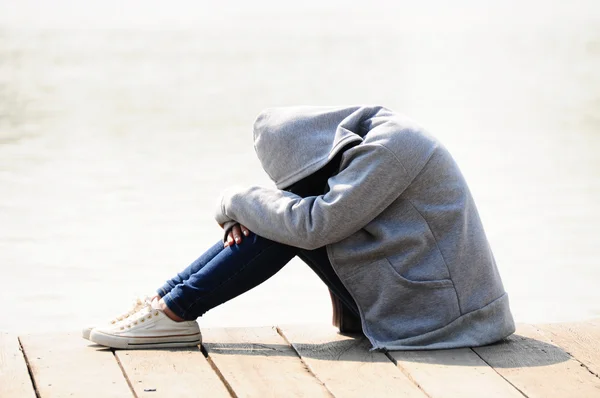 Nära håll ledsen kvinna kram hennes knä sitter nära floden — Stockfoto