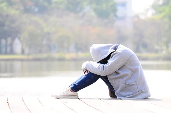 Sad woman hug her knee sitting near river — Stock Photo, Image