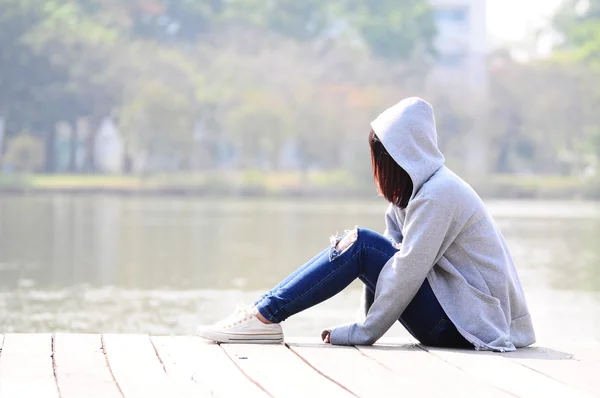 Upset and depressed woman sitting near river — Stock Photo, Image