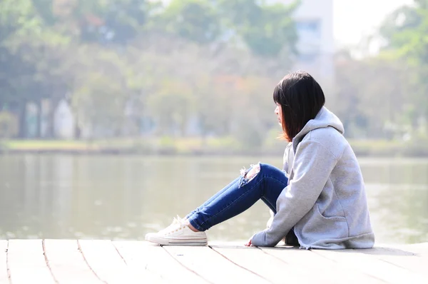 Femme bouleversée assise près de la rivière — Photo