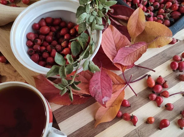 Harvest of juicy rose hips on a baking sheet and rose hip tea close-up.