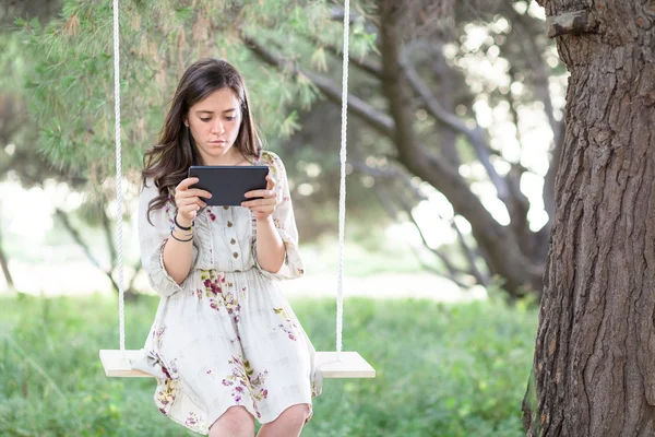 Mujer con Tablet en un columpio — Foto de Stock