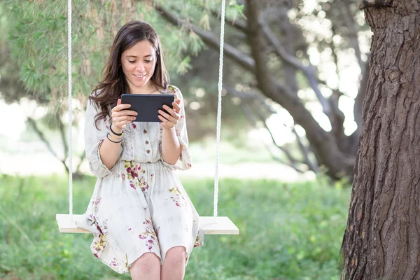 Mujer con Tablet en un columpio — Foto de Stock