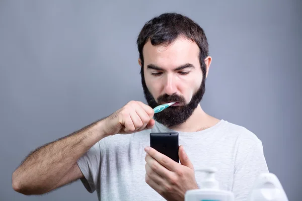 Homme avec brosse à dents et Smartphone Image En Vente