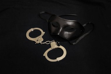 Siyah arka planda bir çift kelepçe ve siyah maske. BDSM