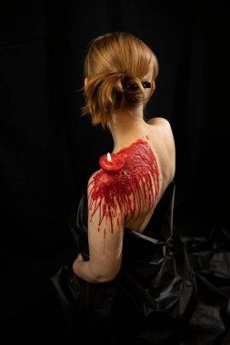 Red wax on back of young submissive woman. Close up. BDSM