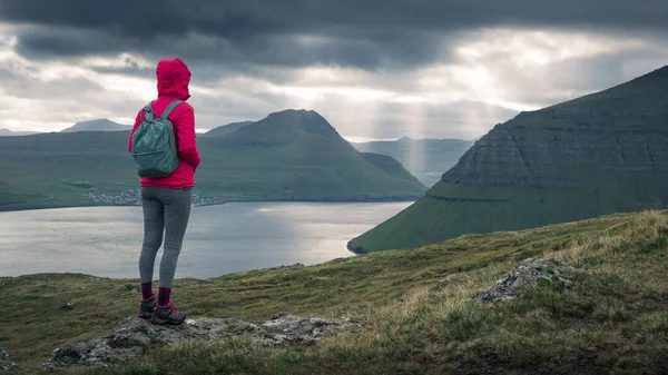 Vrouw Wandelen Met Regenjas Rugzak Voor Lichtstralen Door Dramatische Wolken Rechtenvrije Stockfoto's