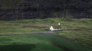 Streymoy Adası 'ndaki Saksun Körfezi' ndeki kilise Faroe Adaları 'ndaki gökyüzünde kara yağmur bulutları.