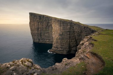 Vagar adasındaki sarp kayalıklar. Okyanus ve günbatımı, Faroe Adaları.
