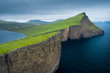 Vagar Adası kıyısındaki sarp kayalıklar Leitisvatn Gölü ve yukarıdaki Faroe Adaları kıyı şeridi.