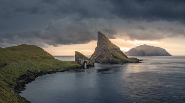 Günbatımında Drangarnier kaya oluşumları ve Tindholmur adası Vagar, Faroe Adaları 'nda bulutlarla