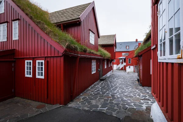 Torshavn, Faroe Adaları 'ndaki Tinganes hükümet bölgesindeki kırmızı binalardan geçerek.