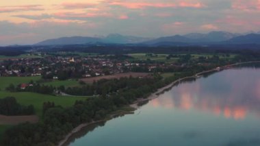 Bavyera 'daki Chiemsee Gölü' nde gün batımında Alp dağlarıyla birlikte, Chieming Köyü 'nde yaz boyunca yanlamasına uçtular.