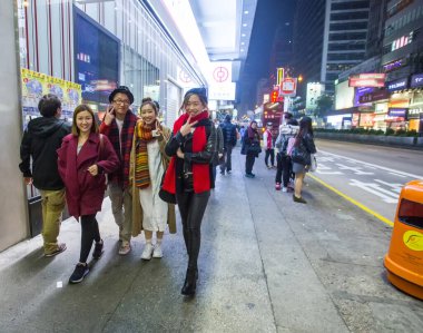 1-22-2015 Hong Kong. Kowloon bölgesinin sokaklarında genç insanlar, gece. Açık büfeler Asya tarzı sokak tarzıdır. Geceleri modern neon reklam panoları,