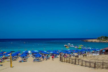Ağustos 'ta Protaras' ın yanındaki inanılmaz Protaras plajı (İncir ağacı körfezi) Akdeniz tatil köyü! Tanınmayan kişiler. Yamaç paraşütü yapan biri. Gökyüzünde küçük bir nokta. Paragliding kişi - gökyüzünde küçük bir nokta