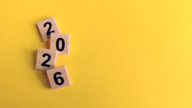 2026 ahşap sayılar, parlak sarı bir arkaplan üzerinde, Yeni Yılı sembolize ediyor, gelecek zaman çizelgesi, yıllık planlama ve parlak fırsatlar.