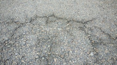 Çatlak Gri Asfalt Dokusunun Yakın Çekimi: Altyapı ve Grunge Arkaplanı için Çakıl ve Örümcek Ağı Çatlakları ile Belirlenmiş Çatı Yüzeyi