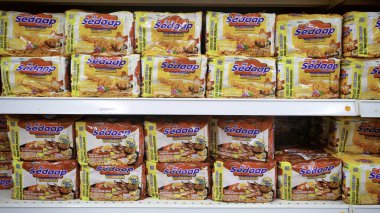 KULIM, MALAYSIA - 9., 2025: Bakkal rafına istiflenmiş farklı tavuk ve barbekü aromalı Mi Sedaap hazır şehriye paketleri.